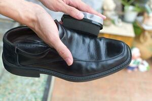 Hands polish leather black shoes. photo