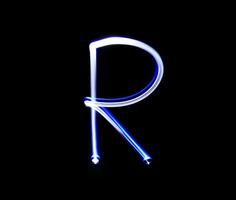 R Romeo alphabet hand writing blue light  over black background. photo