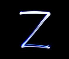 Z Zulu alphabet hand writing blue light  over black background. photo
