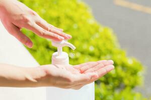 Female hands using wash hand sanitizer gel pump dispenser. photo