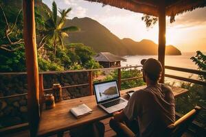 a man sitting at a table with a laptop and a view of the ocean photo