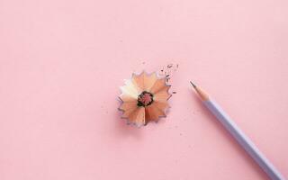 Pencil on a pink background with shavings. Simple purple pencil photo