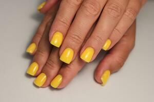 amarillo manicura. cuadrado uñas con gel polaco. soleado y brillante manicura foto