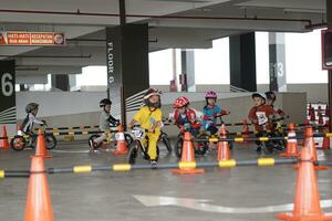 Depok-Indonesia, 29 07 2023 - Indonesian kids from 2-5 years old races on balance bike in a parking area, sportmanship training photo