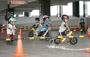 Depok-Indonesia, 29 07 2023 - Indonesian kids from 2-5 years old races on balance bike in a parking area, sportmanship training photo