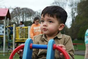 linda asiático pakistaní bebé es disfrutando el hermosa soleado día a Wardown niños y público parque de lutón pueblo de Inglaterra Reino Unido. bajo ángulo imagen estaba capturado en abril 03, 2023 foto