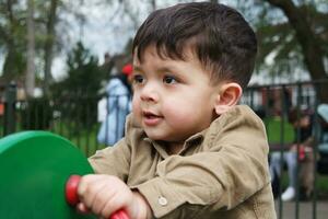 linda asiático pakistaní bebé es disfrutando el hermosa soleado día a Wardown niños y público parque de lutón pueblo de Inglaterra Reino Unido. bajo ángulo imagen estaba capturado en abril 03, 2023 foto