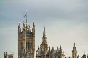 Beautiful Low Angle View of Historical Big Ben Clock Tower from river Thames and London Eye, Westminster Central London, England Great Britain, UK. Image Captured During Cloudy Day of August 2nd, 2023 photo