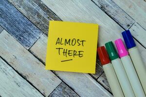 Concept of Almost There write on sticky notes isolated on Wooden Table. photo