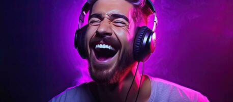 Male vocalist in recording studio enjoying music with open mouth wearing headphones and exhibiting joy and positivity hipster style against purple backdro photo