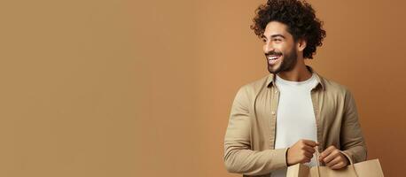 Young man with curly hair shopping carrying bags on neutral background New collection or Sales mockup photo