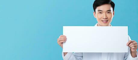 Portrait of a young Asian doctor with a blank board on a blue background a concept of healthcare in a medical setting photo