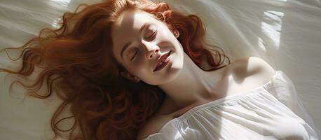 A young woman with red hair and a smile lies on a studio floor with a white background photo