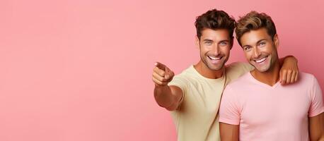Gay couple smiling pointing in opposite directions over pink background photo