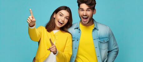 Two enthusiastic friends in casual attire isolated in front of a yellow backdrop display approval by pointing and showing thumbs up photo