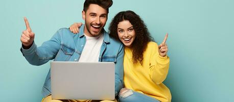 Young couple friends in casual clothes excitedly posing with laptop on yellow background photo