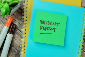 Concept of Incident Report write on sticky notes isolated on Wooden Table. photo