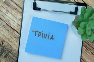 Concept of Trivia write on sticky notes isolated on Wooden Table. photo