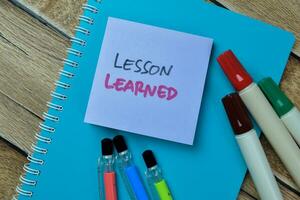 Concept of Lesson Learned write on sticky notes isolated on Wooden Table. photo