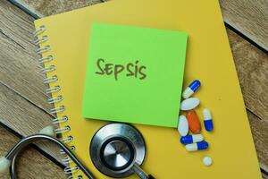 Concept of Sepsis write on sticky notes with stethoscope isolated on Wooden Table. photo