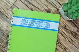 Concept of Environmental Protection Laws and Regulations write on book isolated on Wooden Table. photo