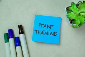 Concept of Staff Training write on sticky notes isolated on Wooden Table. photo