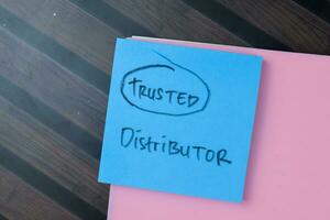 Concept of Trusted Distributor write on sticky notes isolated on Wooden Table. photo