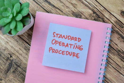 Concept of Standard Operating Procedure write on sticky notes isolated on Wooden Table. photo