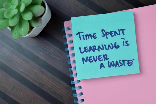 Concept of Time Spent Learning Is Never Waste write on sticky notes isolated on Wooden Table. photo