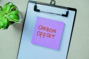 Concept of Carbon Offest write on sticky notes isolated on Wooden Table. photo