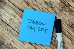 Concept of Carbon Offset write on sticky notes isolated on Wooden Table. photo