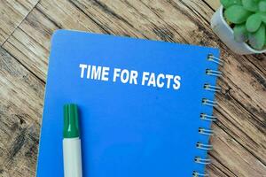 Concept of Time For Facts write on book isolated on Wooden Table. photo