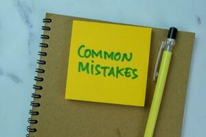 Concept of Common Mistakes write on sticky notes isolated on Wooden Table. photo