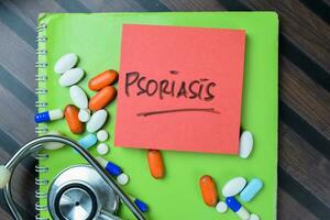 Concept of Psoriasis write on sticky notes with stethoscope isolated on Wooden Table. photo