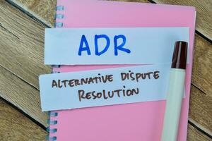 Concept of ADR - Alternative Dispute Resolution write on sticky notes isolated on Wooden Table. photo