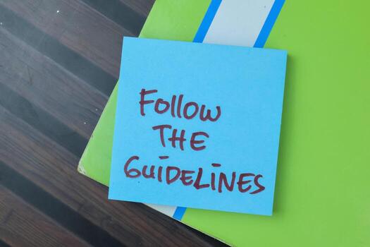 Concept of Follow The Guidelines write on sticky notes isolated on Wooden Table. photo