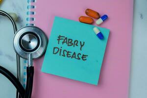 Concept of Fabry Disease write on sticky notes with stethoscope isolated on Wooden Table. photo