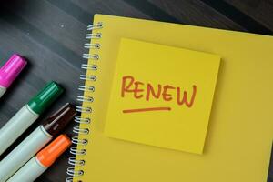 Concept of Renew write on sticky notes isolated on Wooden Table. photo