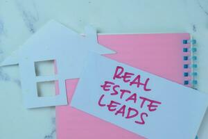 Concept of Real Estate Leads write on sticky notes isolated on Wooden Table. photo