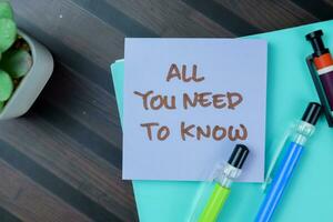 Concept of All You Need To Know write on sticky notes isolated on Wooden Table. photo