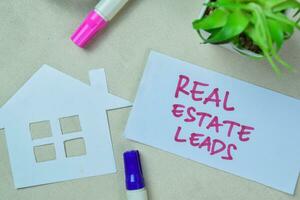 Concept of Real Estate Leads write on book isolated on Wooden Table. photo