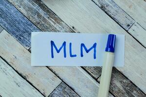 Concept of MLM write on sticky notes isolated on Wooden Table. photo
