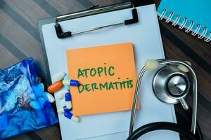 Concept of Atomic Dermatitis write on sticky notes with stethoscope isolated on Wooden Table. photo