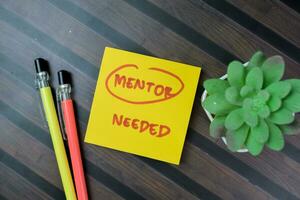 Concept of Mentor Needed write on sticky notes isolated on Wooden Table. photo