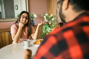 Young diverse loving couple eating croissant and talks together at home in breakfast time. Communication and relationship concept photo