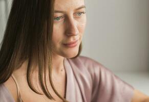 Melancholy young woman near window at home portrait, closeup. photo