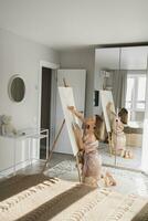 Young woman artist painting on canvas on the easel at home in bedroom - art and creativity concept photo