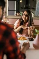 Happy couple eating breakfast and talking at dining table in morning. Indian girl and latino guy. Relationship and diversity concept photo