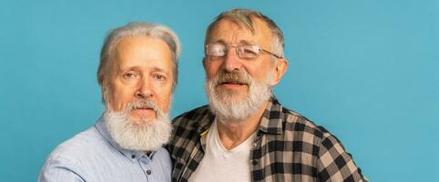 Banner portrait two elderly man friends standing over blue background - friendship, aged and senior people photo