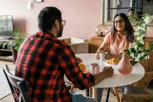 Young diverse loving couple eating croissant and talks together at home in breakfast time. Communication and relationship concept photo